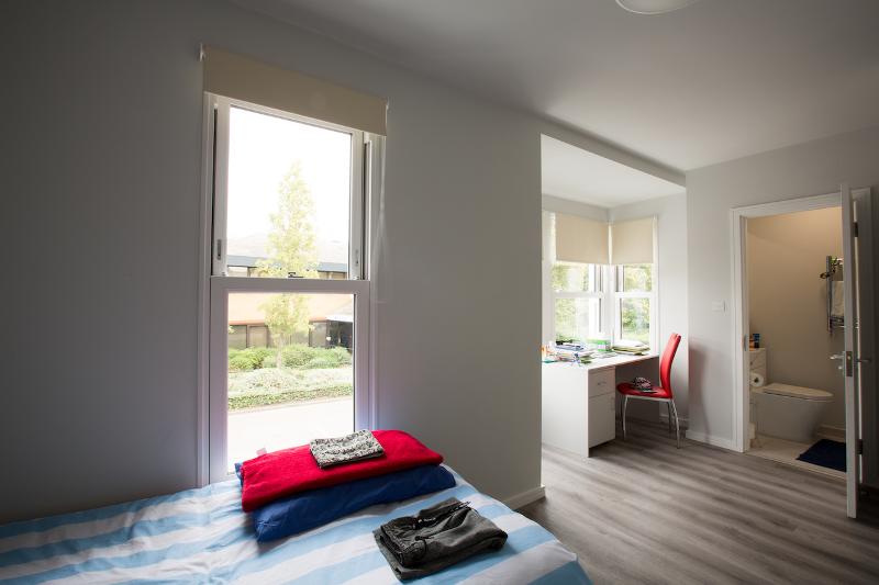 Kamer in residentie met bed met gestreept beddengoed tijdens de taalcursussen buitenland
