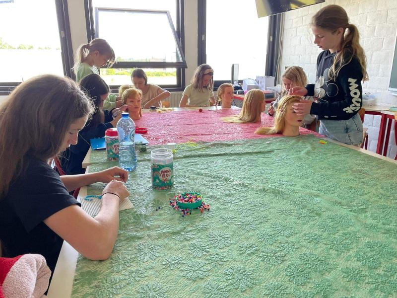 Meisjes aan het knutselen en doen het haar tijdens het meidenkamp