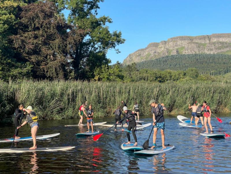 Deelnemers van een jongerenreis suppen als activiteit in een plas water