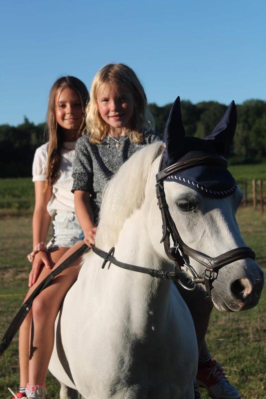 twee meisjes samen op een paard tijdens paardrijdenkamp zomer