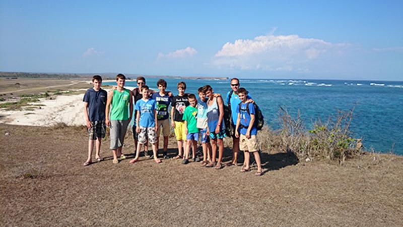 Deelnemers van een groepsreis Indonesië staan met elkaar op de foto op een klif met de zee op de achtergrond