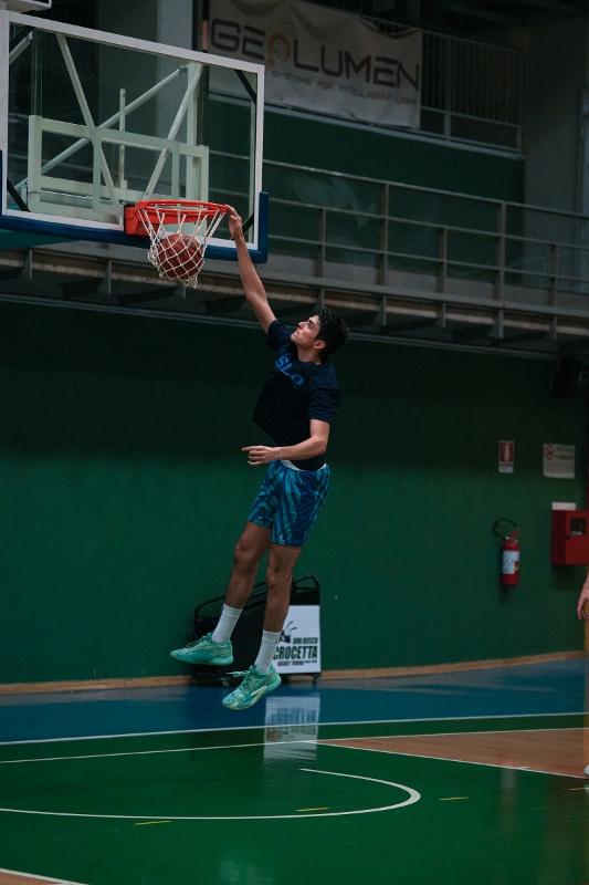Jongen scoort tijdens een internationaal kamp Jongen is aan het basketballen tijdens basketbalkamp