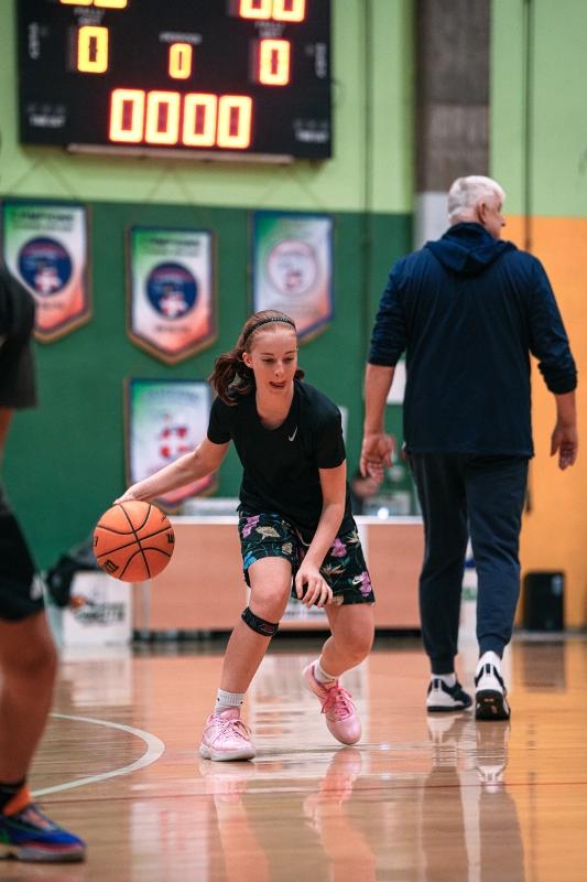 Meisje op een internationaal kamp speelt basketbal Meisje is aan het basketballen op een basketbalkamp