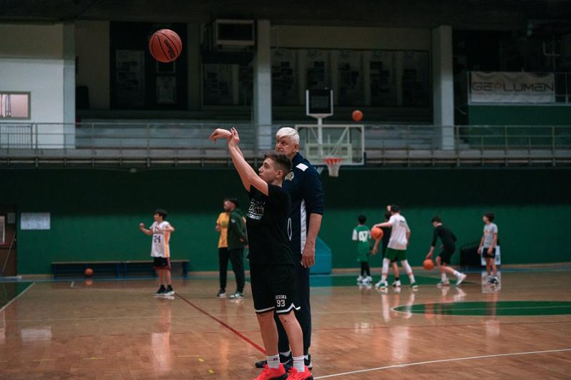 Jongen schiet een basketbal op een internationaal kamp Jongen is aan het leren basketballen tijdens basketbalkamp