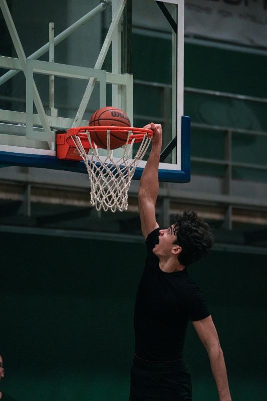 Jongen schiet bal is de ring tijdens basketbalkamp