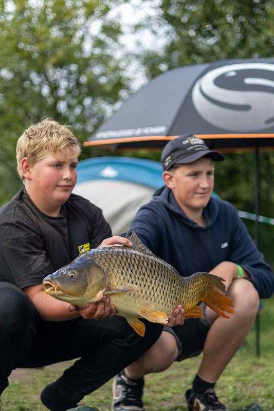 Tijdens een viskamp Lommel kun je mooie vissen vangen Twee jongens zitten gehurkt met grote vis in hun handen tijdens een viskamp Lommel
