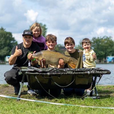 Groepje kinderen en begeleider met grote karper tijdens het viskamp Aalst 